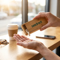 Tapping a capsule from the open Seedroot bamboo on-the-go supplement case into an open palm at a sunlit cafe