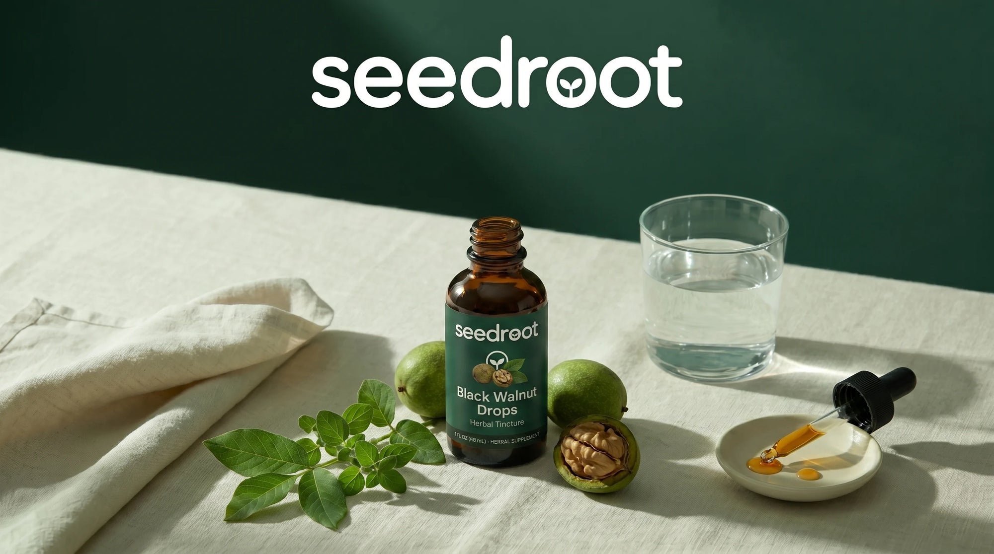 Seedroot Black Walnut Drops dropper bottle on a linen table with fresh black walnuts, walnut leaves, a glass of water and a dropper — your wellness journey