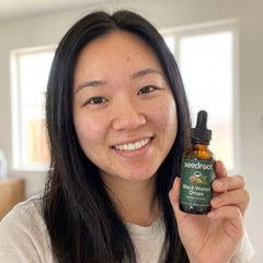 Smiling Seedroot customer holding the Black Walnut Drops amber dropper bottle