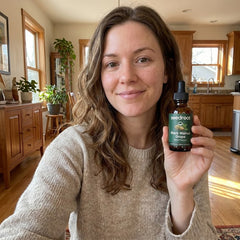 Seedroot customer holding the Black Walnut Drops dropper bottle in a sunlit room