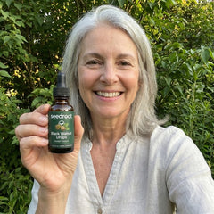 Silver-haired woman holding Seedroot Black Walnut Drops outdoors