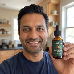 Man in a bright kitchen holding Seedroot Black Walnut Drops