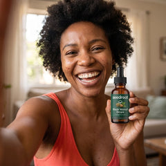 Smiling woman holding Seedroot Black Walnut Drops in her living room