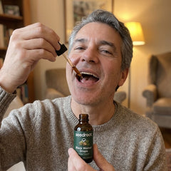 Man taking Seedroot Black Walnut Drops with the glass dropper under his tongue