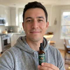 Young man holding the Seedroot Black Walnut Drops dropper bottle