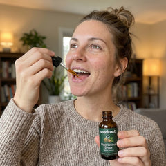 Woman taking Seedroot Black Walnut Drops with the glass dropper